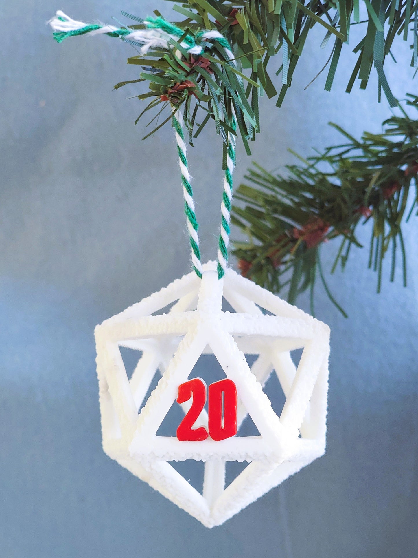 Geometric Christmas ornament with number '20' hanging on a tree branch.